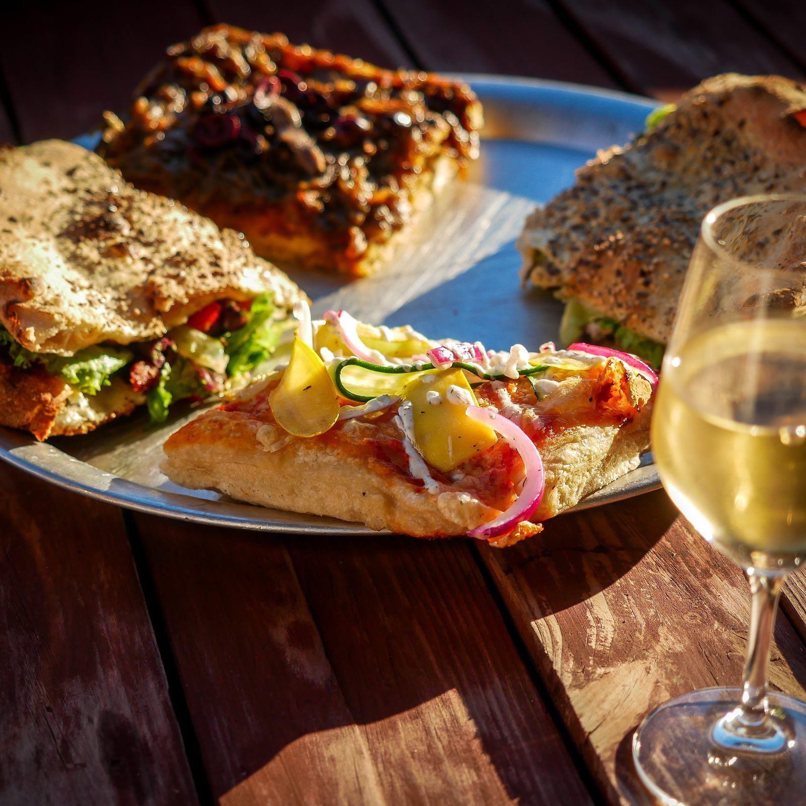 Assiette de pizza à la coupe et de focaccia garnie, verre de vin blanc